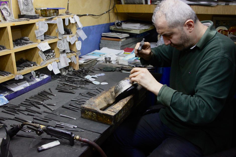 Złotnik grawerujący metal młotkiem przy stole narzędziowym w Lacjum