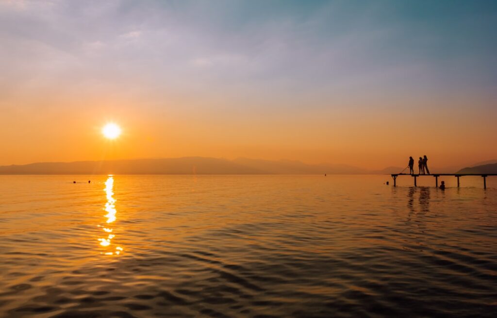 Couple tasting wine by the lakeside at sunset