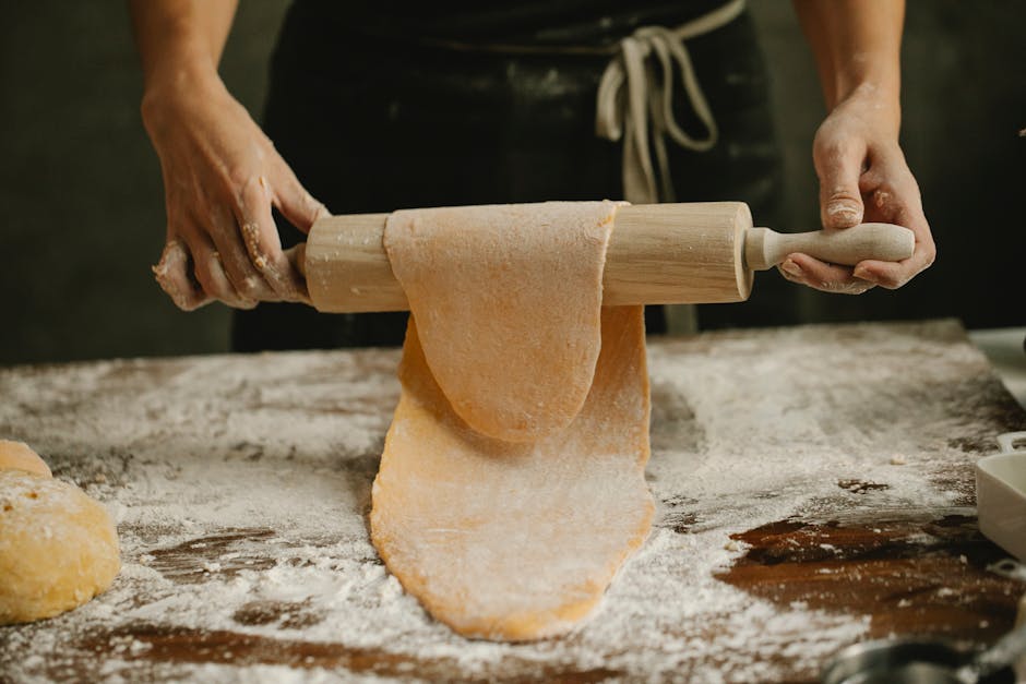 Mani che stendono pasta fresca durante laboratorio di cucina nel Lazio