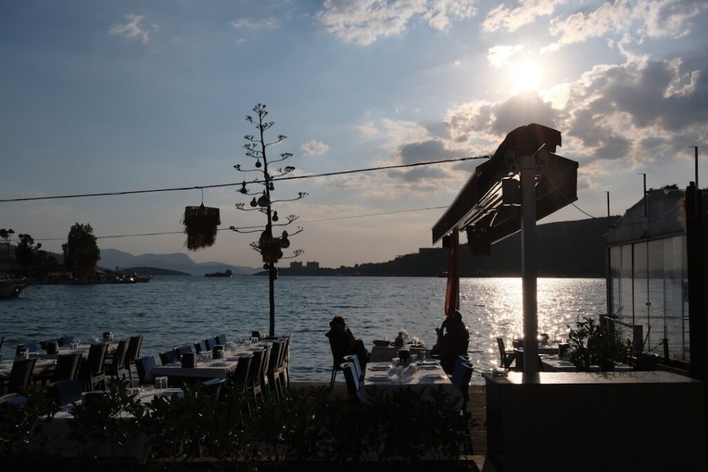 Sunlit lakeside restaurant tables set along Lake Albano at dusk