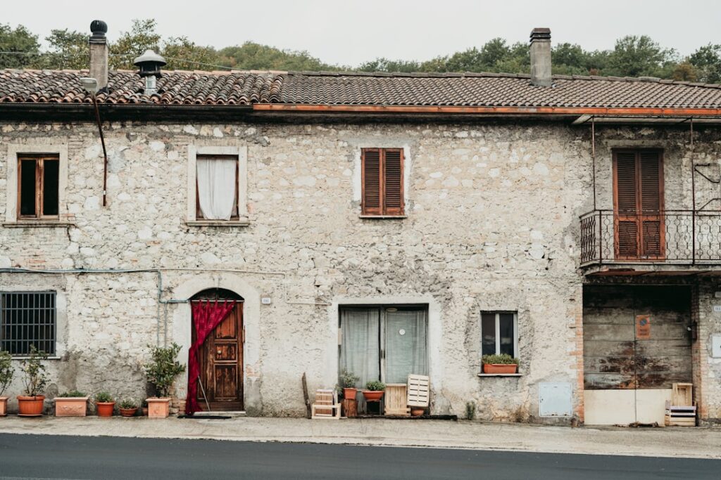 Facciata in pietra di casa con vasi e porta rossa, Lazio