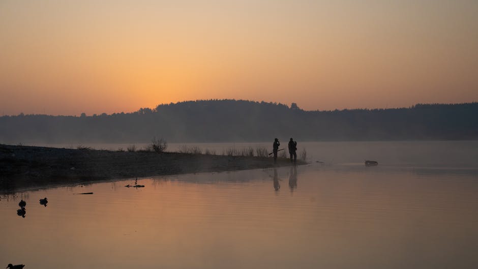 Zwei Angler am Ufer des Bracciano-Sees bei Sonnenaufgang