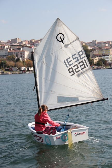Młoda żeglarka na łodzi typu Optimist pływająca po jeziorze Bracciano