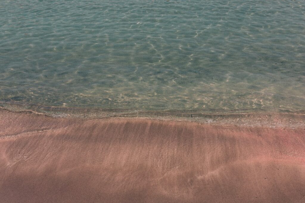 Roze zand en kristalhelder water op Kreta strand, rustige kustlijn