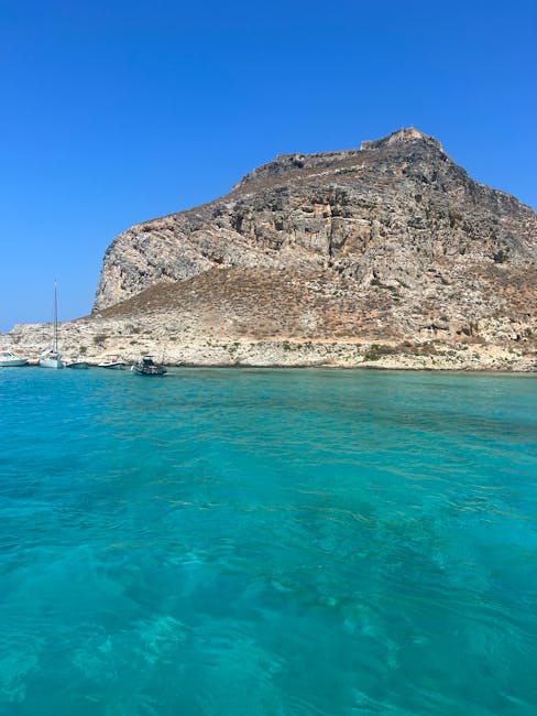 Rotsachtig eiland bij Kreta met zeilboten en turquoise zee