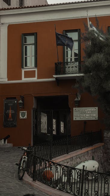Fasada Muzeum Wojny na Krecie z flagą i zaparkowanym rowerem