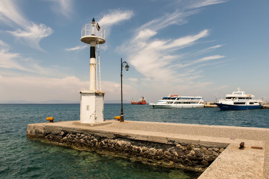 Havenpier met wit vuurtorentje en boten aan de kust van Kreta