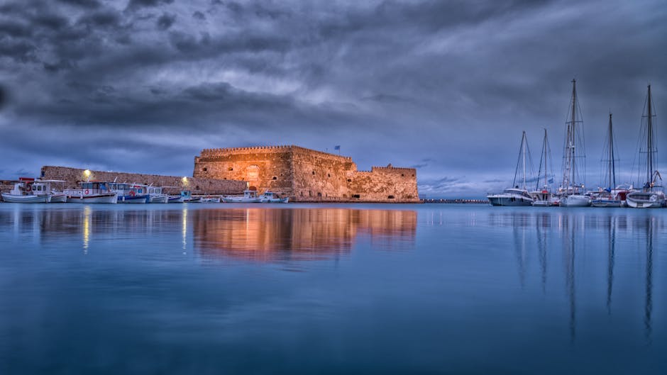 Verlicht Koules-fort reflecteert in kalm water bij avond in Heraklion