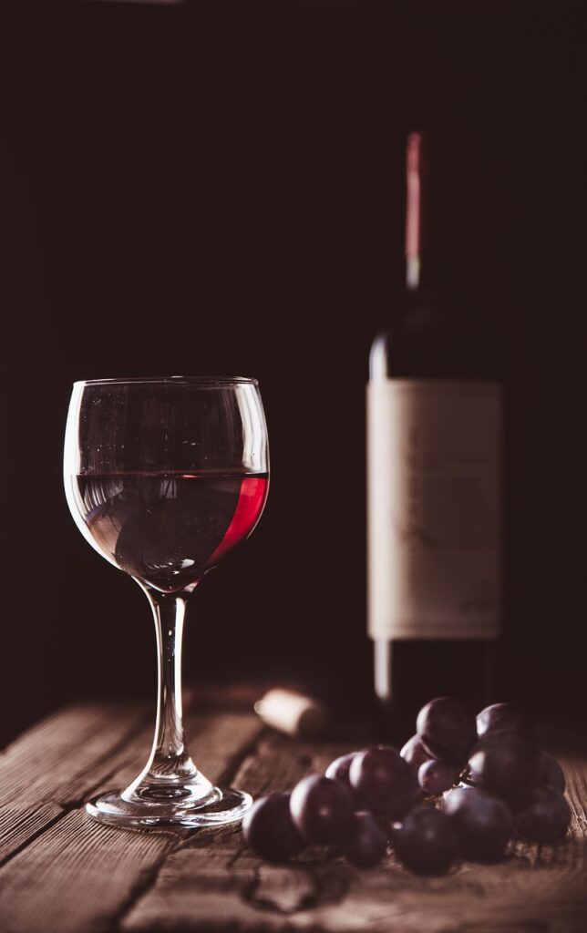 Glas rode wijn met druiven en fles op houten tafel in Kreta