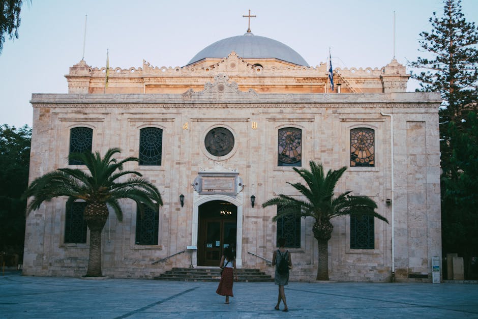 Façade d'un bâtiment à dôme et croix, palmiers devant, Crète