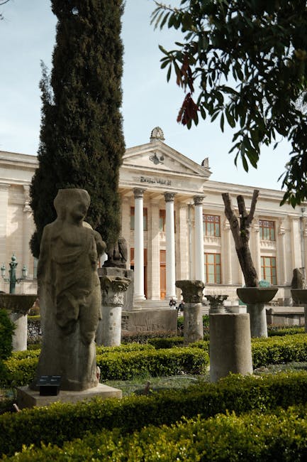 Façade néoclassique d'un musée en Crète entourée de statues et cyprès