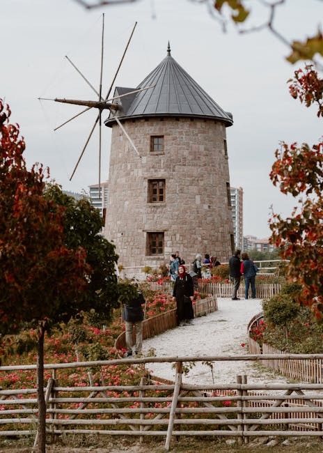 Moulin à vent en pierre entouré de visiteurs et jardins en Crète
