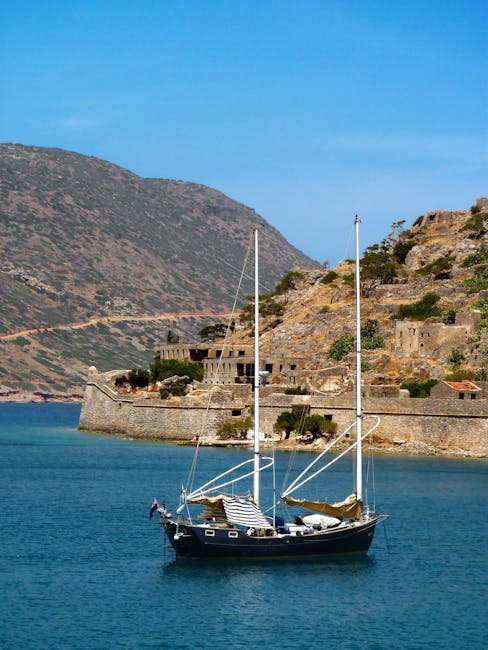 Zeilboot voor de vestingmuur van Spinalonga, rotsachtige kust van Kreta