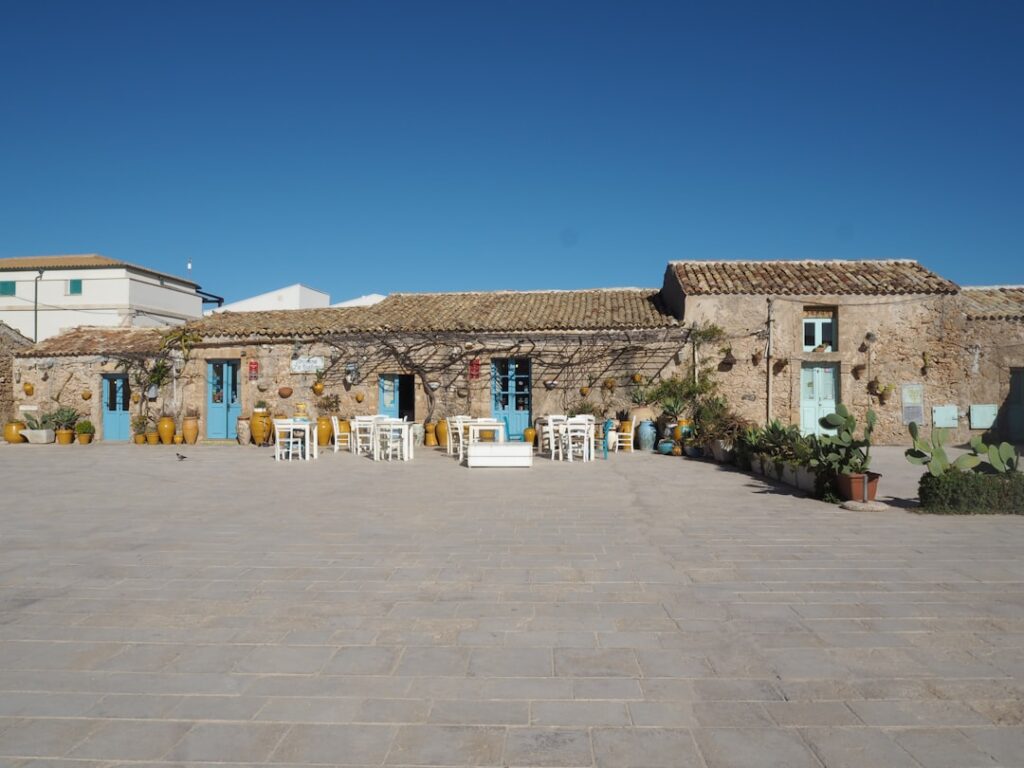 Maison en pierre en Crète, portes bleues et tables extérieures