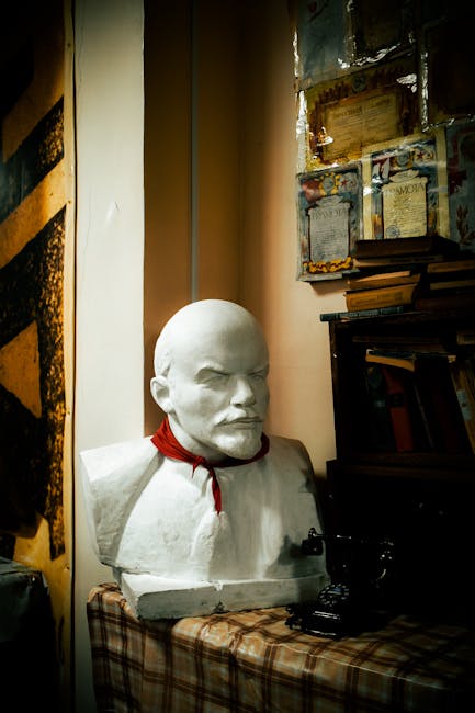 Buste en plâtre d'un homme barbu coiffé, foulard rouge posé près de livres
