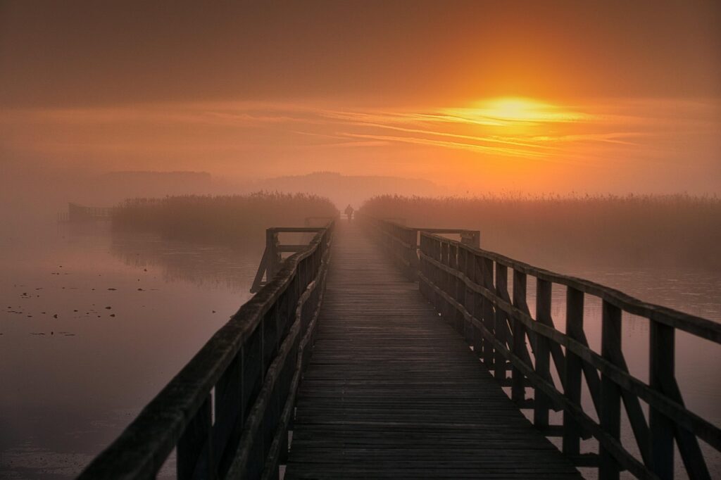 Passerelle en bois s'enfonçant dans la brume au lever de soleil en Crète