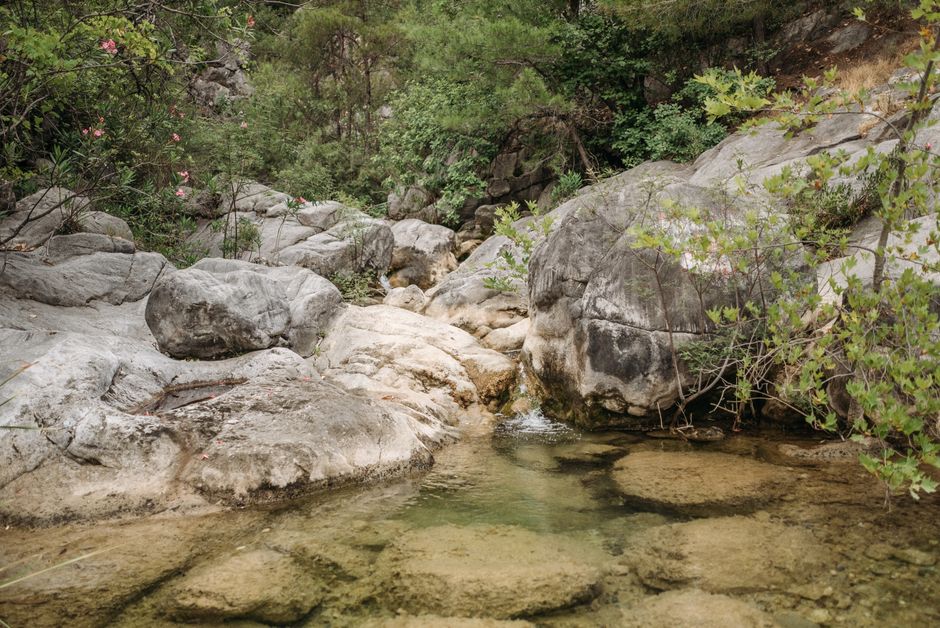 Kleine heldere bergpoel tussen afgeronde rotsen en groen op Kreta