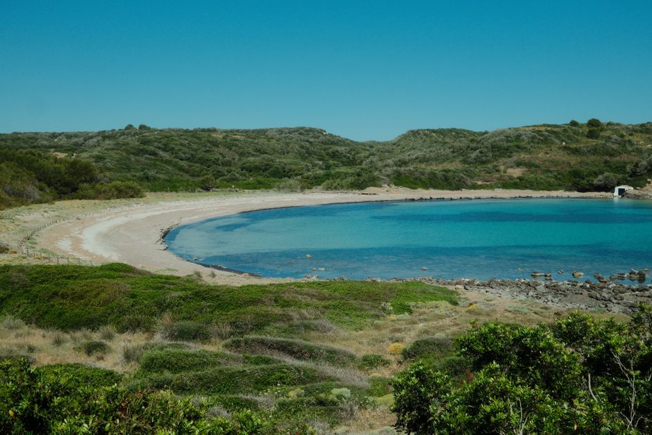 Kromme zandbaai omringd door duinen en struiken op Kreta