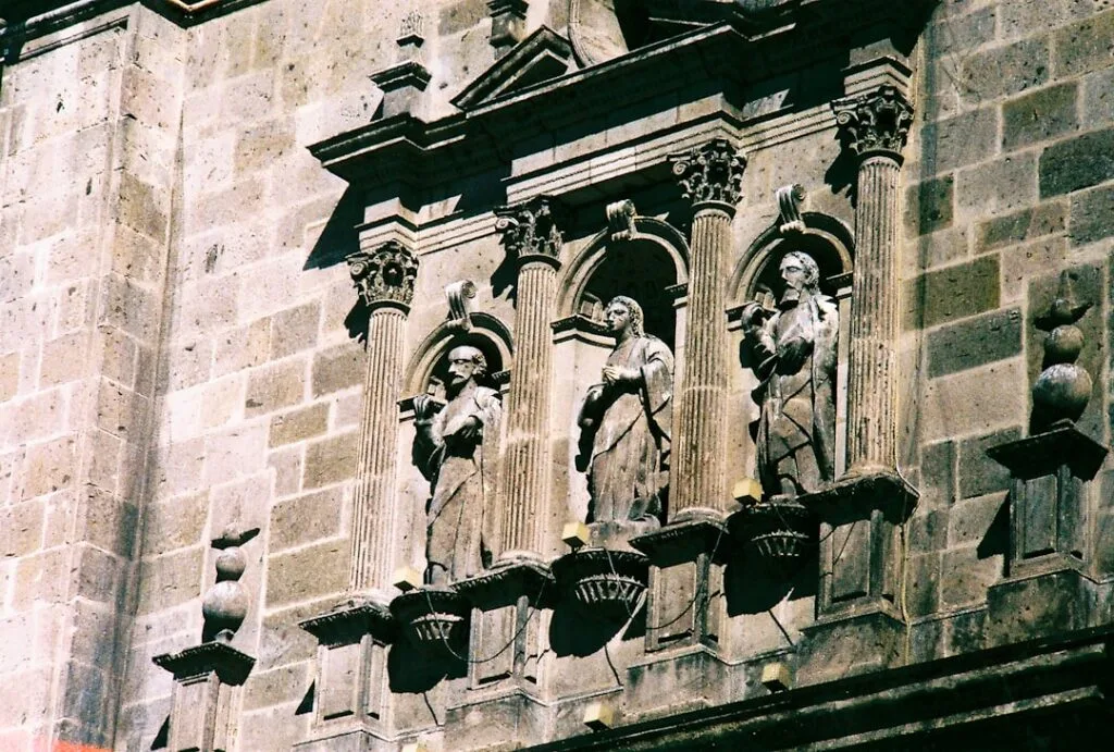 trois statues en pierre dans des niches sur une façade siennoise