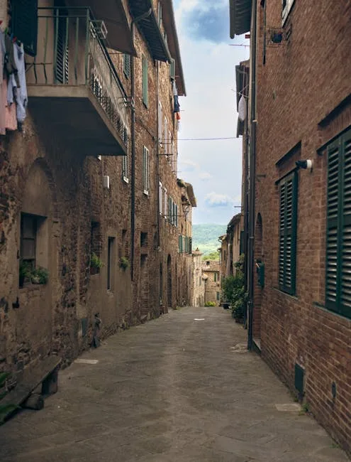Ruelle pavée de Sienne bordée de maisons en pierre, vue campagnarde