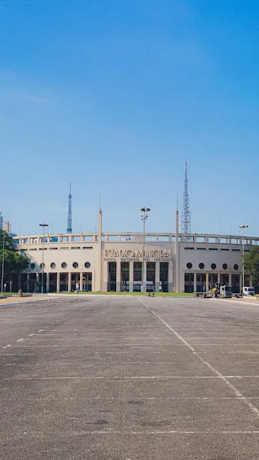 Façade d'un stade municipal avec grand parking vide au premier plan