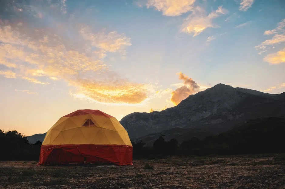 Dôme de tente coloré planté au crépuscule devant des montagnes