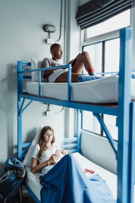 Chambre de dortoir avec lits superposés et deux voyageuses se détendant