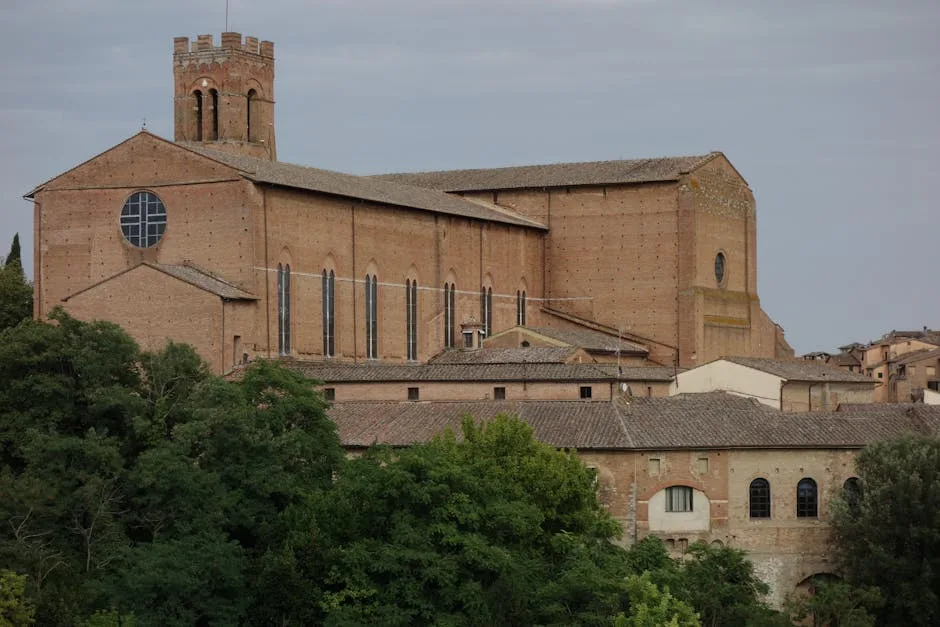 Basilique en brique dominant les toits et les arbres de Sienne