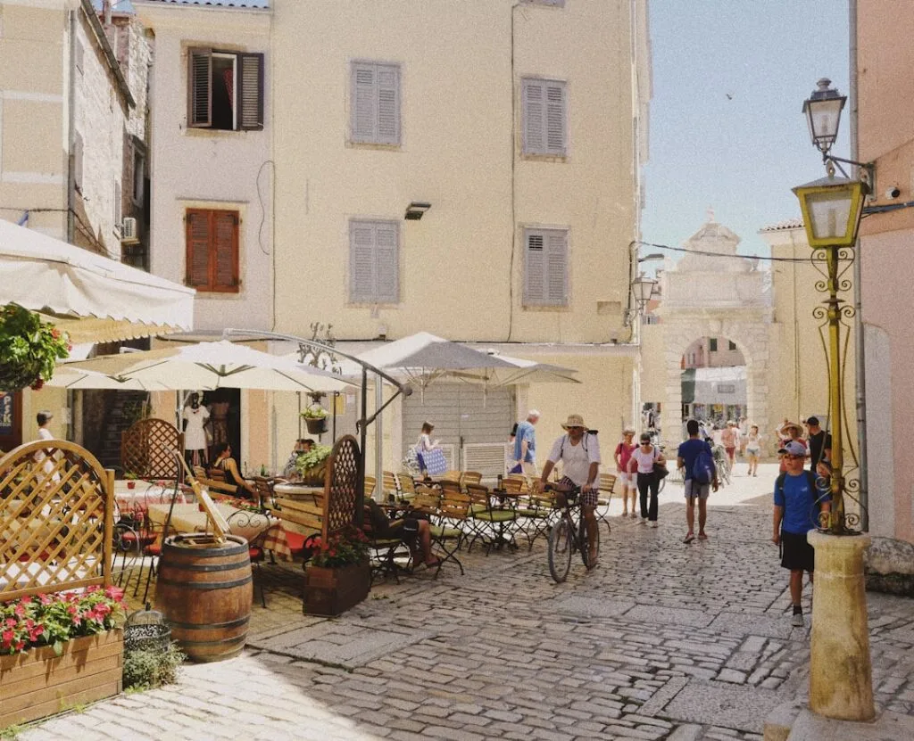 Ruelle pavée animée avec terrasse de café et passants