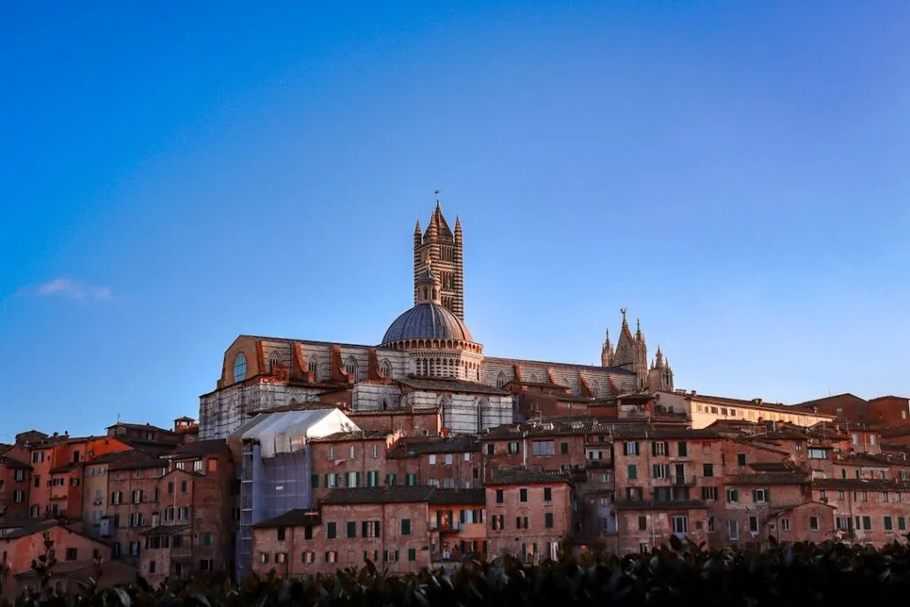 Silhouette du Duomo de Sienne dominant les toits rouges au crépuscule