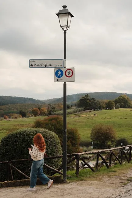 Panneau vers Monteriggioni sur lampadaire, promeneuse devant campagne près de Sienne