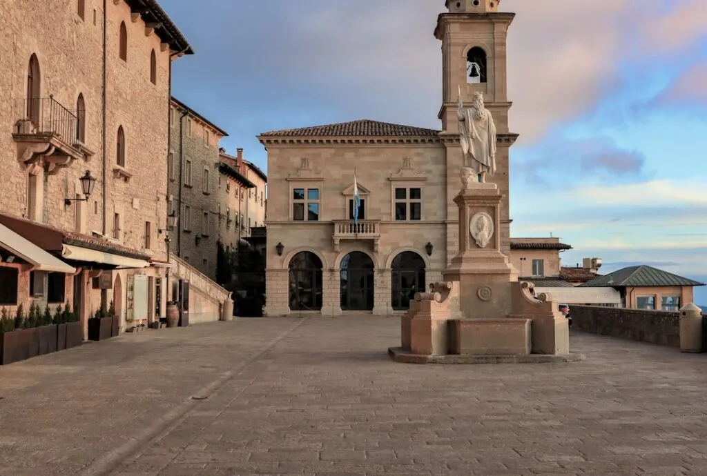 Place pavée vide avec statue centrale et bâtiment à clocher