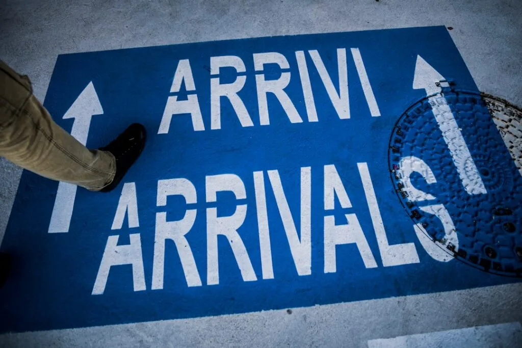 Marquage au sol bleu 'ARRIVALS' avec un pied franchissant la zone