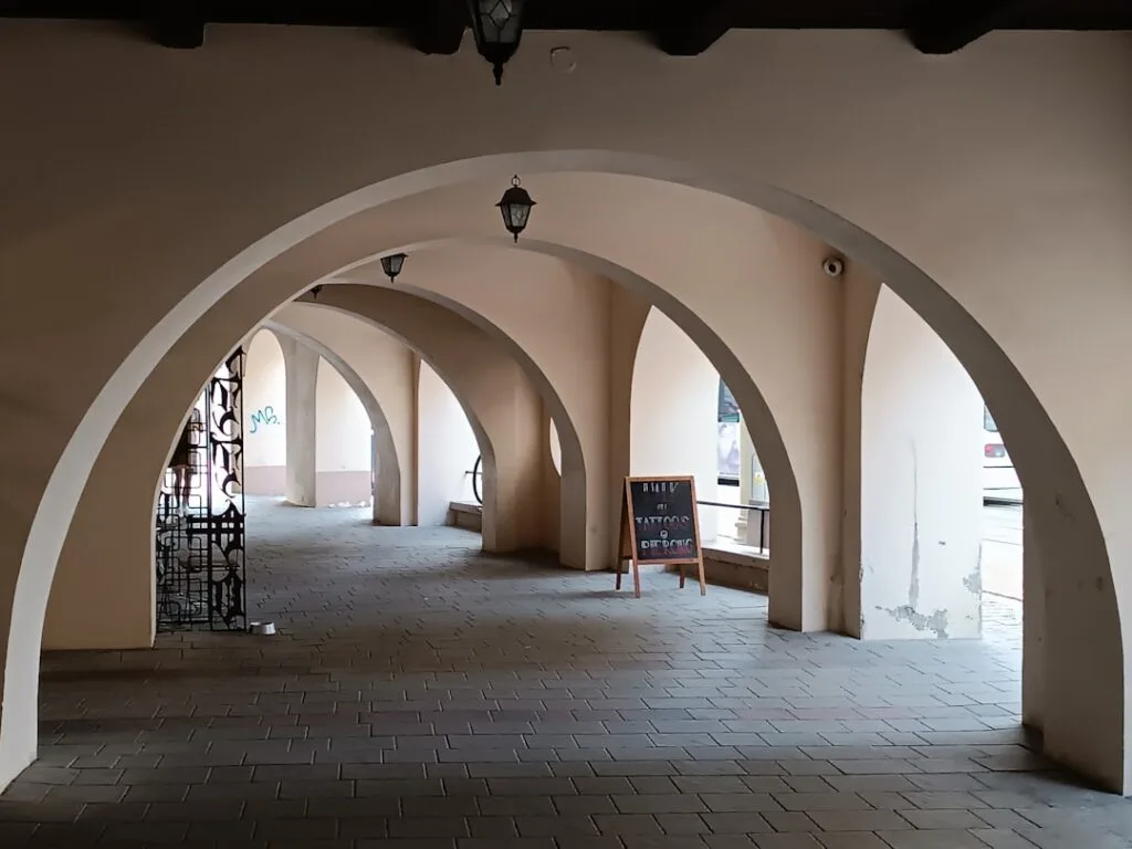 Voûtes et arcades beiges formant un passage couvert à Sienne