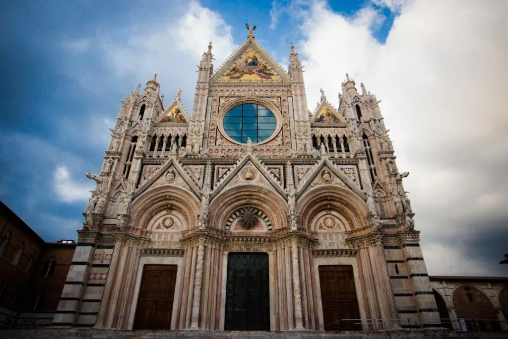 Façade richement sculptée du Duomo de Sienne sous un ciel dramatique