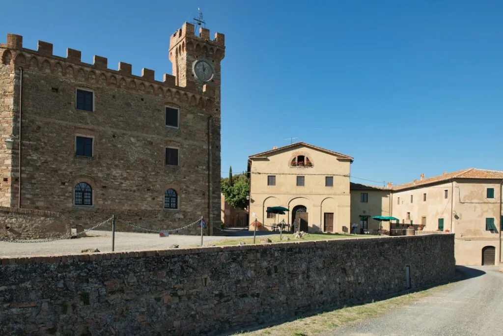 Bâtiment fortifié avec tour horloge dans un village toscan baigné de soleil
