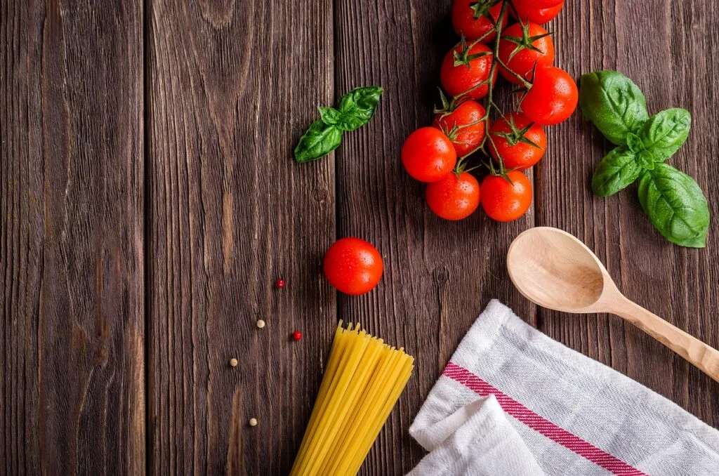 Spaghetti, Kirschtomaten und Basilikum auf rustikalem Holztisch