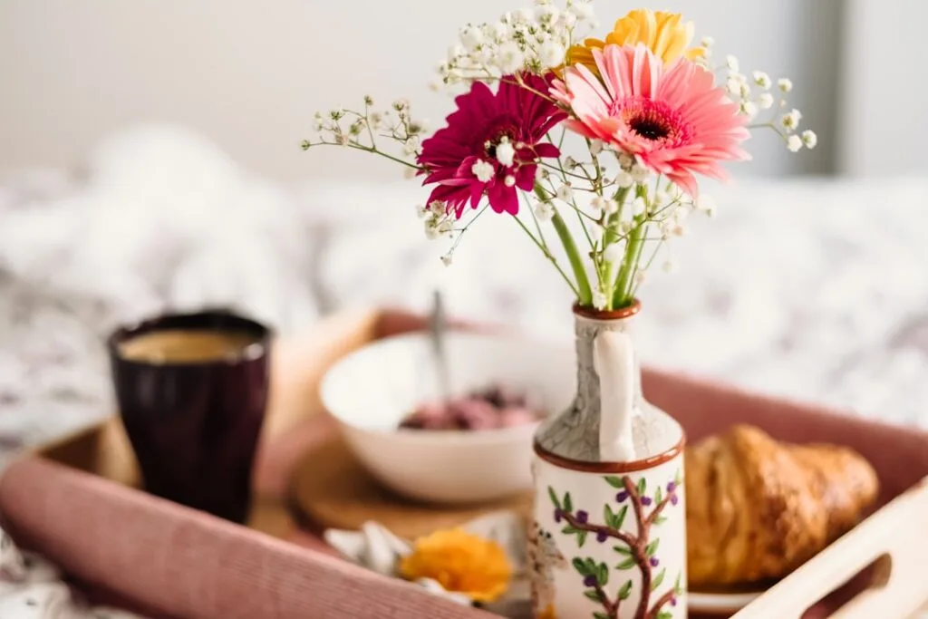 Plateau petit-déjeuner avec fleurs, croissant et tasse de café