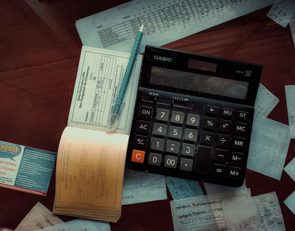 Calculatrice, papiers et stylo sur bureau, notes de dépenses