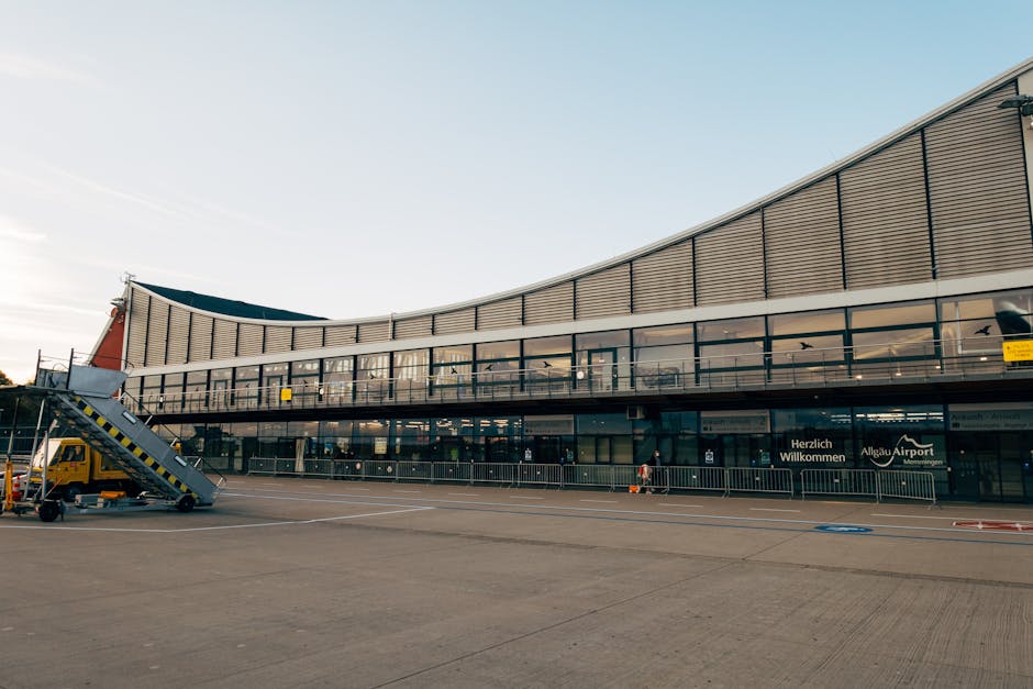 Modern airport terminal building with boarding stairs on empty tarmac.