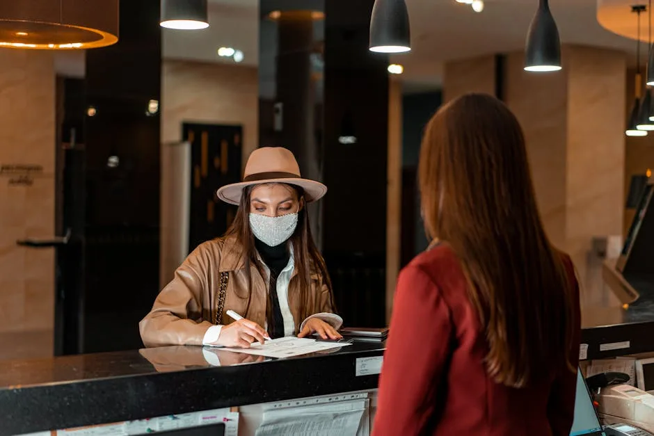 Voyageuse masquée signant des papiers à la réception d'un hôtel