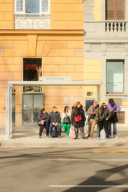 Personnes attendant à un abribus devant un bâtiment ocre à Sienne