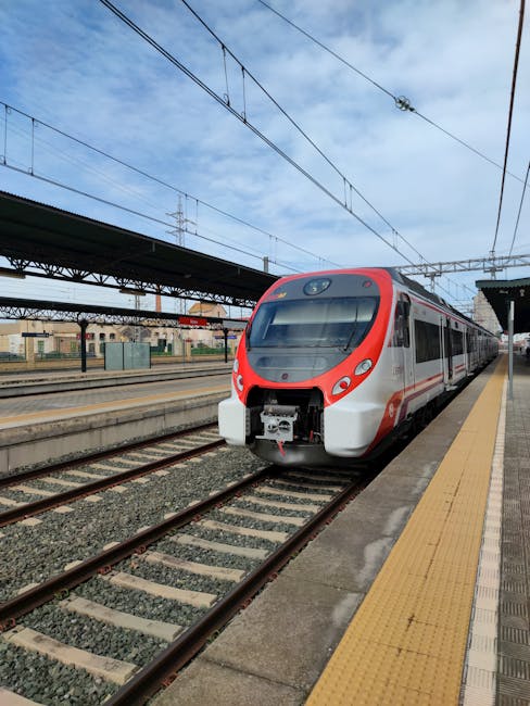 Train régional rouge et blanc à quai, quais et caténaires visibles