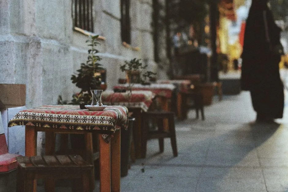 Terrasse étroite avec petites tables couvertes de nappes et verre, ruelle siennoise