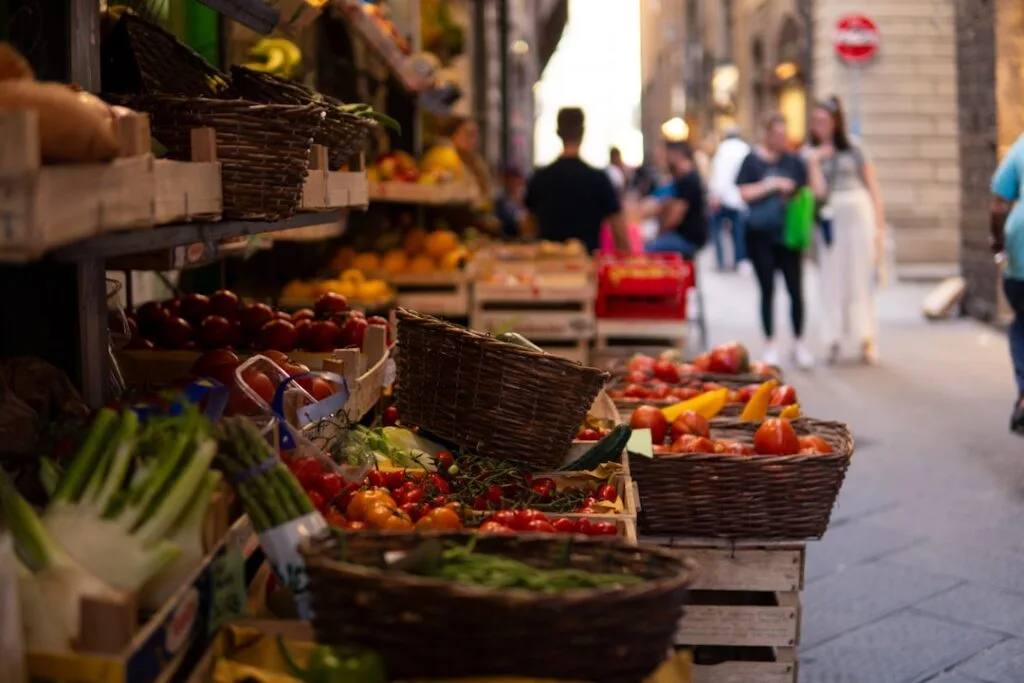 Étal de légumes et fruits en paniers dans une ruelle animée de Sienne