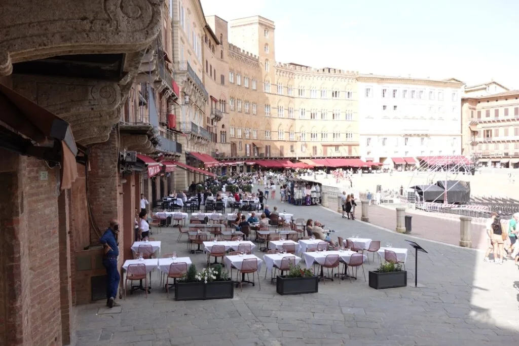 Terrasse de restaurant avec nappes blanches sur la Piazza del Campo à Sienne