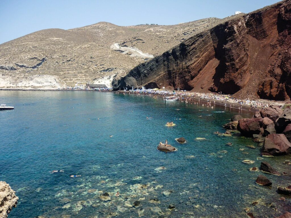 Snorkeling vicino a Red Beach con le scogliere rosse viste dal mare