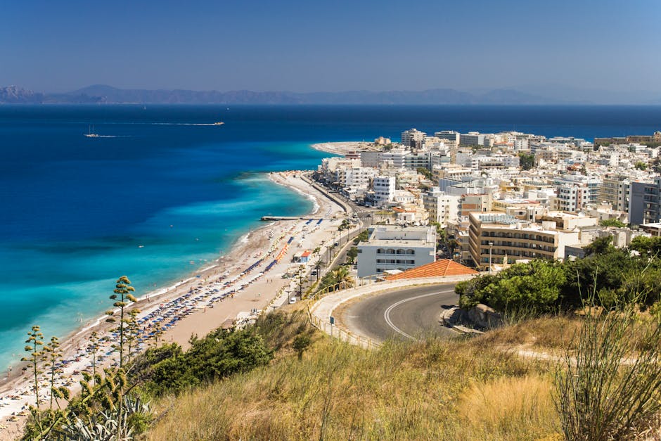 Curving coastal road above Rhodes beach with turquoise Mediterranean waters