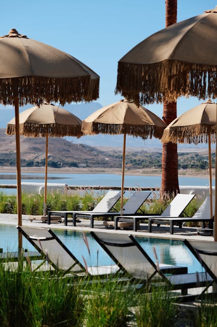Hotelpool mit Liegen und Strohsonnenschirmen, Meerblick auf Rhodos