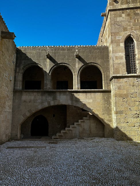 Medieval stone courtyard in Rhodes with arched galleries and pebble flooring